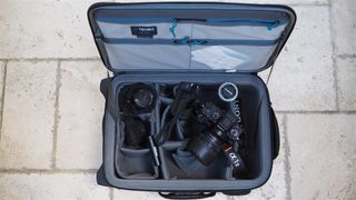 Tenba Roadie Air Case Roller 21 camera bag filled with camera gear on a stone flag floor