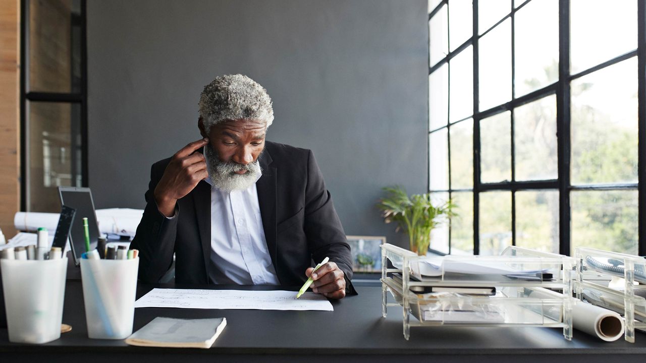 Older man sitting at a desk going through books