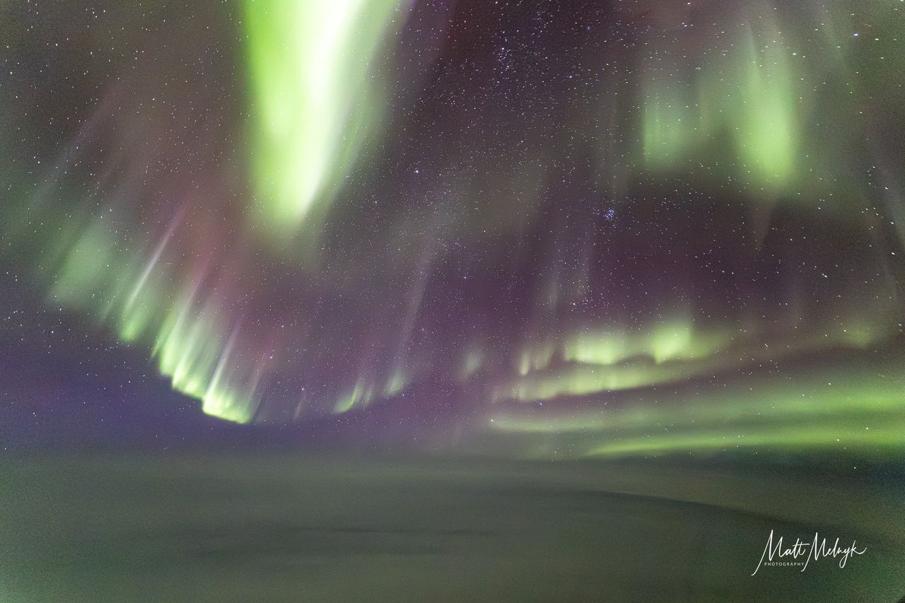 ribbons of green and purple light fill the sky in photos captured above the clouds from a dreamliner airplane.