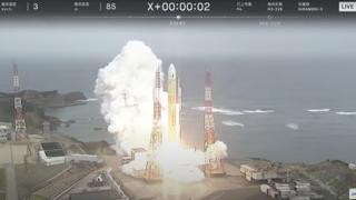 a yellow and white rocket launches from a seaside pad