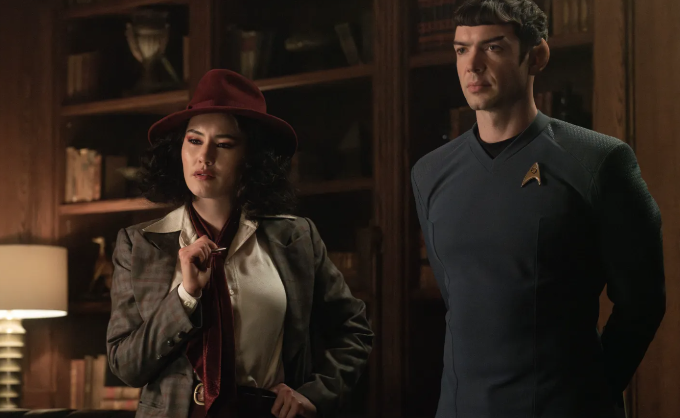 A woman in a vintage outfit stands with an alien sci-fi character
