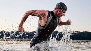 A male triathlete running out of the water