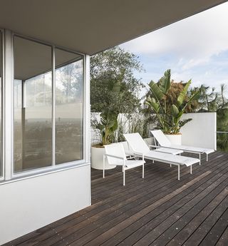 Terrace view of white sun loungers and dark wooden decking