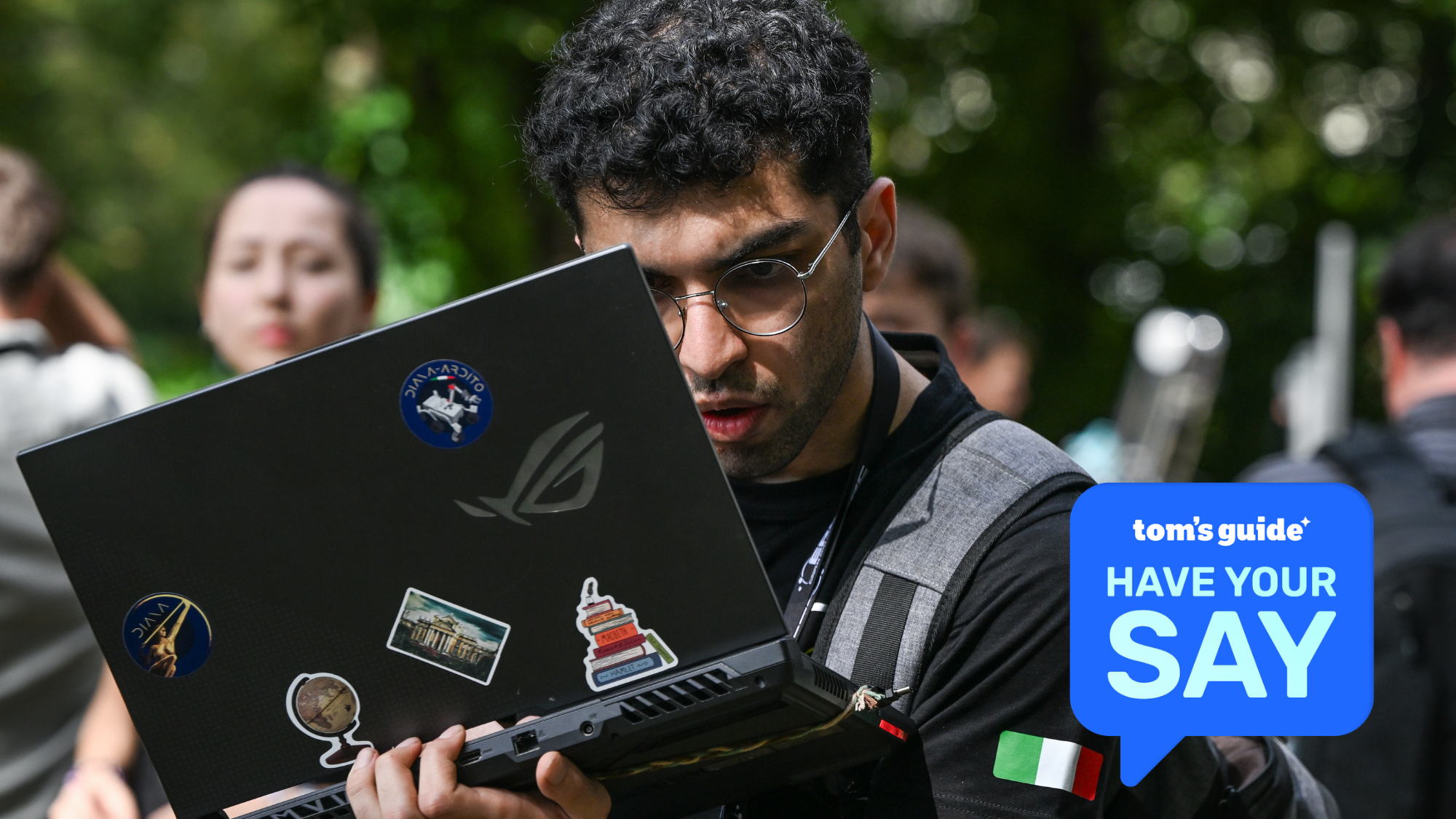 An engineering student carries a laptop controlling a rover in the Mars Rover Challenge.  A graphic with 'Tom's Guide Have Your Say' is overlaid