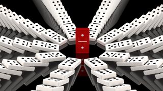 Domino Backdoor malware - A macro shot of a red domino standing upright, surrounded by eight symmetrical lines of fallen white dominoes against a black backdrop