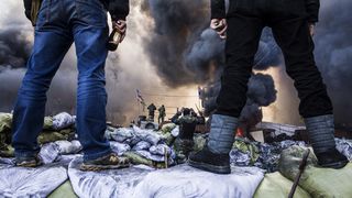 Anti-government demonstrators stand on barricades during clashes with riot police in Kiev on February 18, 2014. Opposition leader Vitali Klitschko on February 18 urged women and children to l