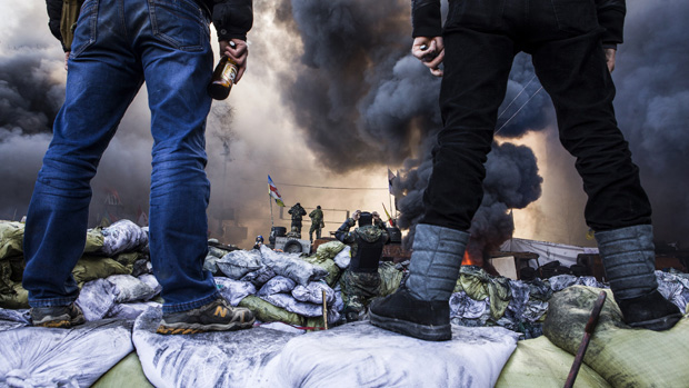 Anti-government demonstrators stand on barricades during clashes with riot police in Kiev on February 18, 2014. Opposition leader Vitali Klitschko on February 18 urged women and children to l