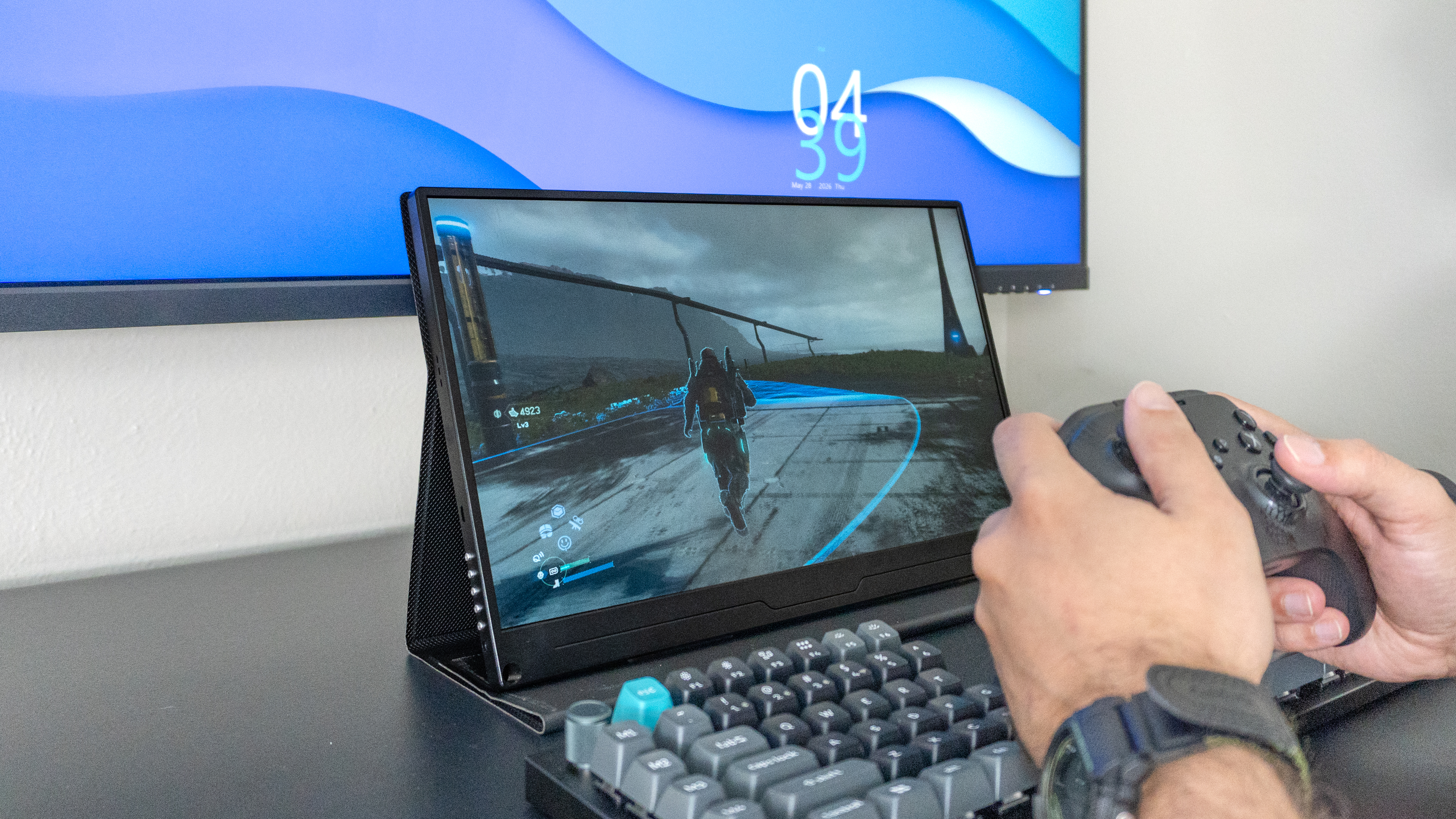 A person playing Death Stranding 2 on a portable monitor using the Geekom A9 Max 2026 Edition