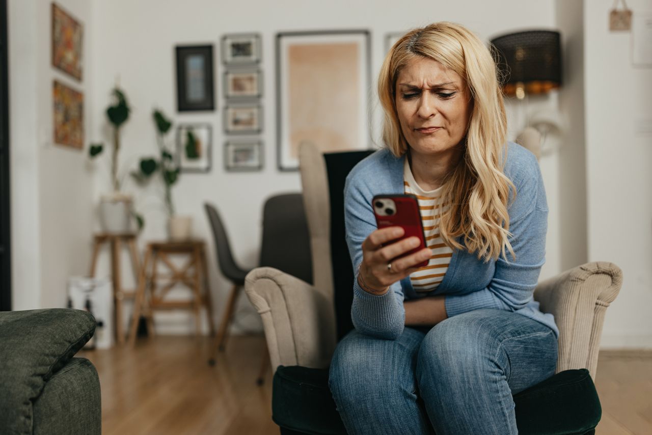 An older woman is upset while looking at her smart phone.