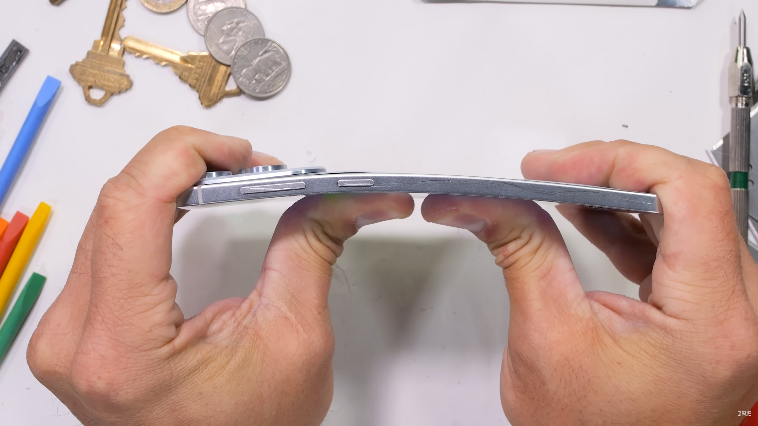 Galaxy S25 Edge durability test by JerryRigEverything, with the phone being bent from the front. The back panel has lifted away from the side rail slightly
