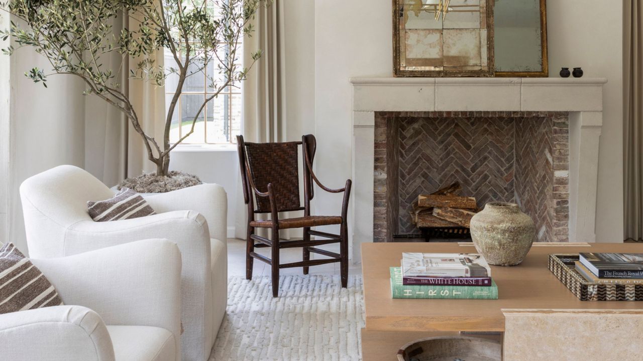 open fireplace with brick herringbone tile, boucle armchairs, potted olive tree, coffee table