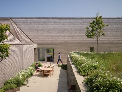 place of work's house in a meadow between the forest and the sea, an architectural, geometric house in leafy countryside