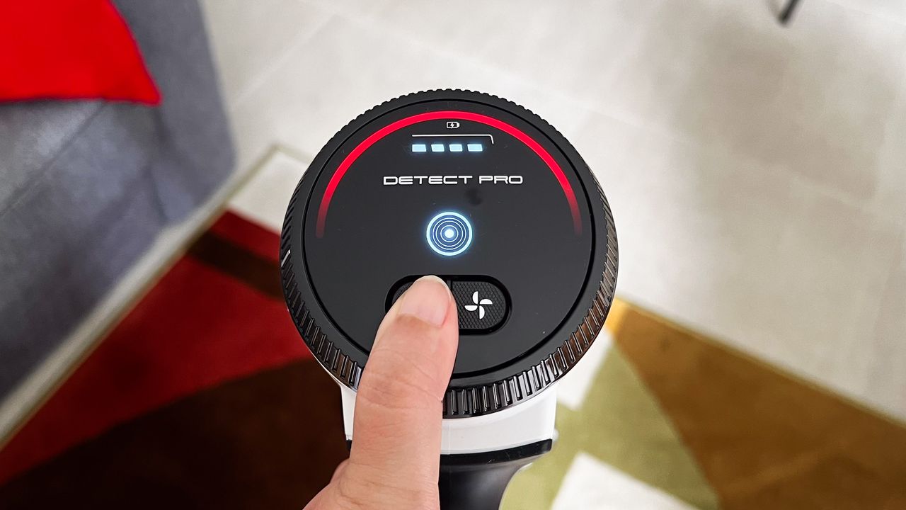 A finger on the power button of the Shark Cordless Detect Pro