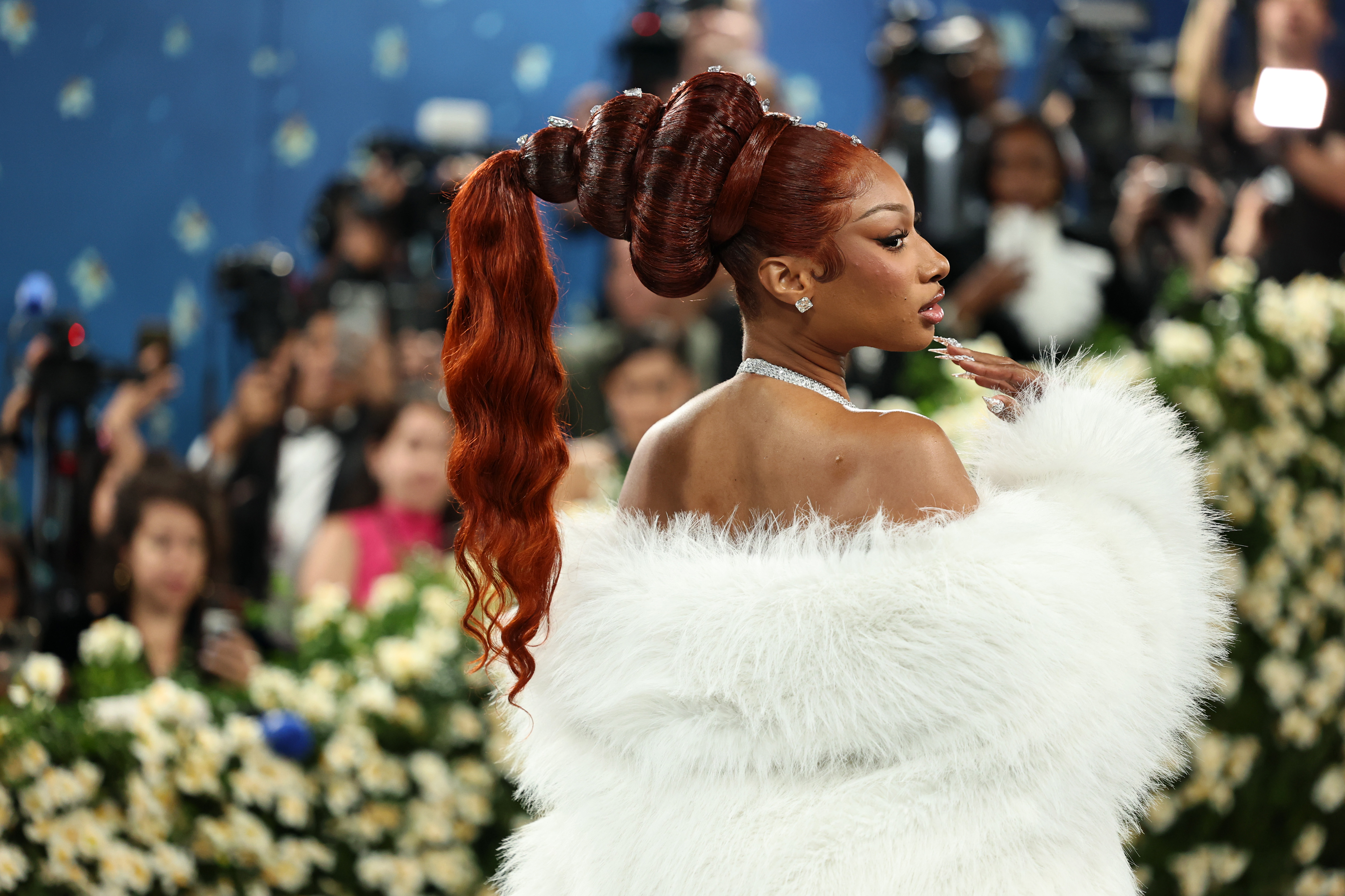 a woman in a white gown with a red ponytail with diamonds
