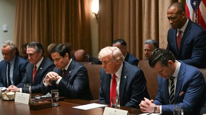 President Donald Trump prays alongside members of his Cabinet during a meeting.