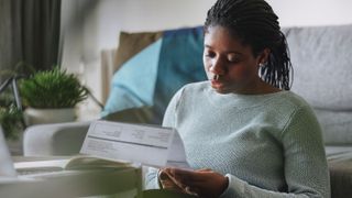 A Young Businesswoman Reading a Utility Bill while Working from Home