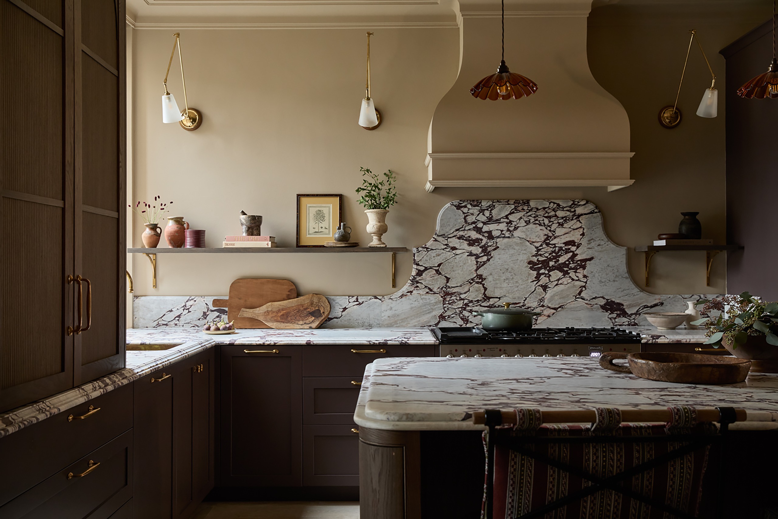 A dark kitchen with a dramatically veined countertop and curves. Lots of decorative elements such as wall lights and shapely details.