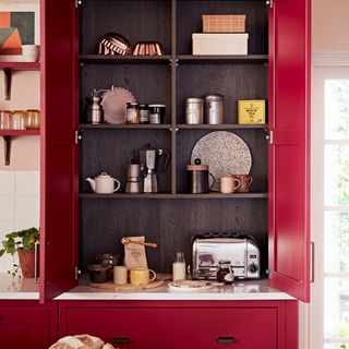 Red kitchen cabinet open with tea and coffee inside