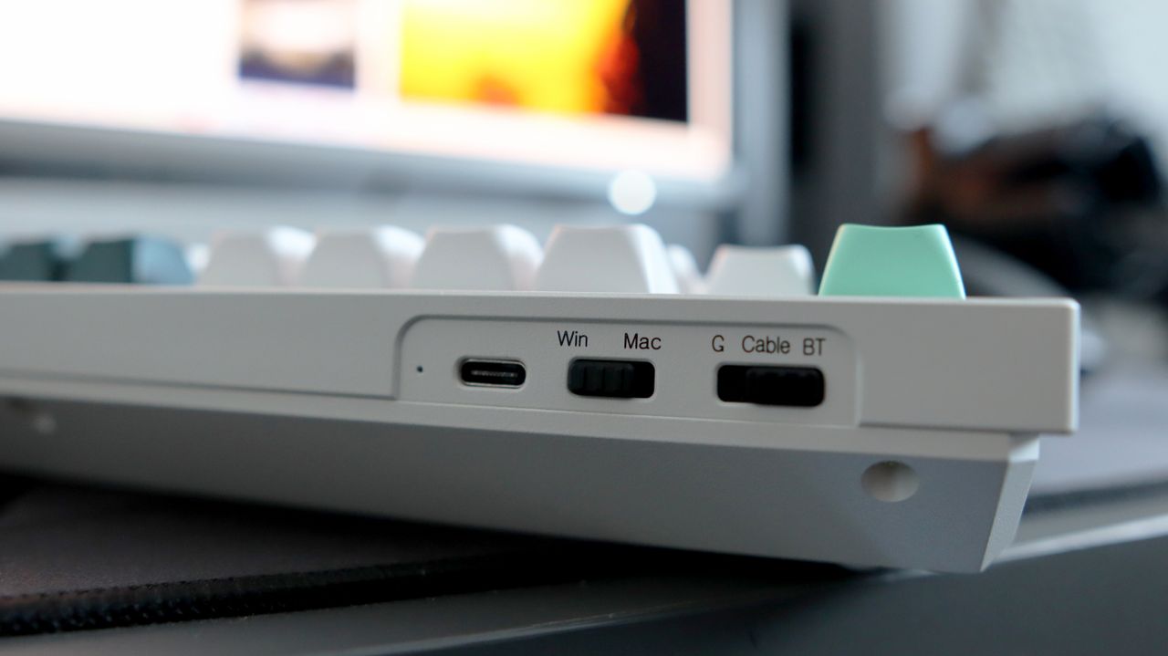 A Keychron Q5 HE gaming keyboard on a desk with white and blue keycaps.