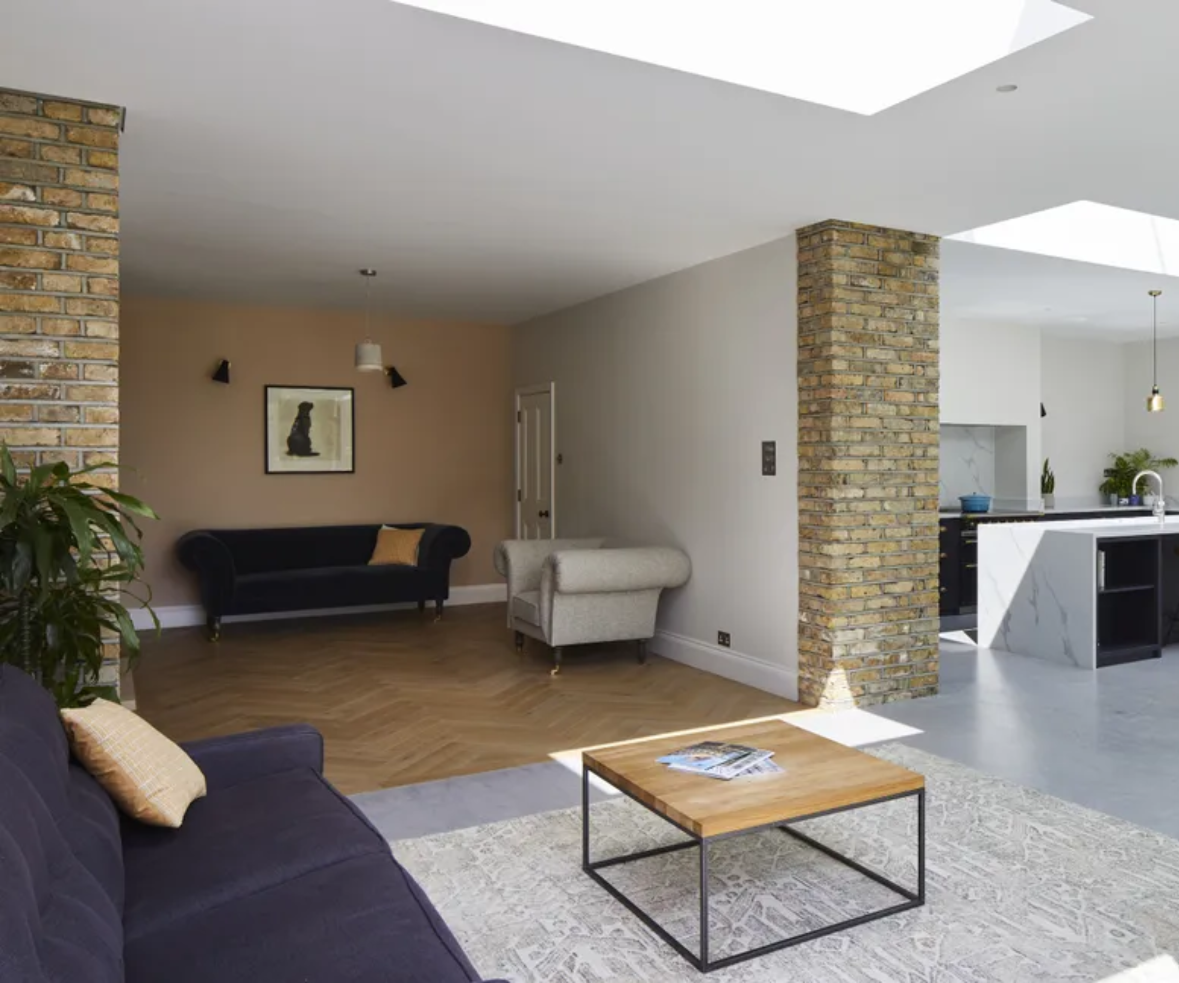 Open plan space with herringbone flooring in snug and grey tiles in kitchen and living area