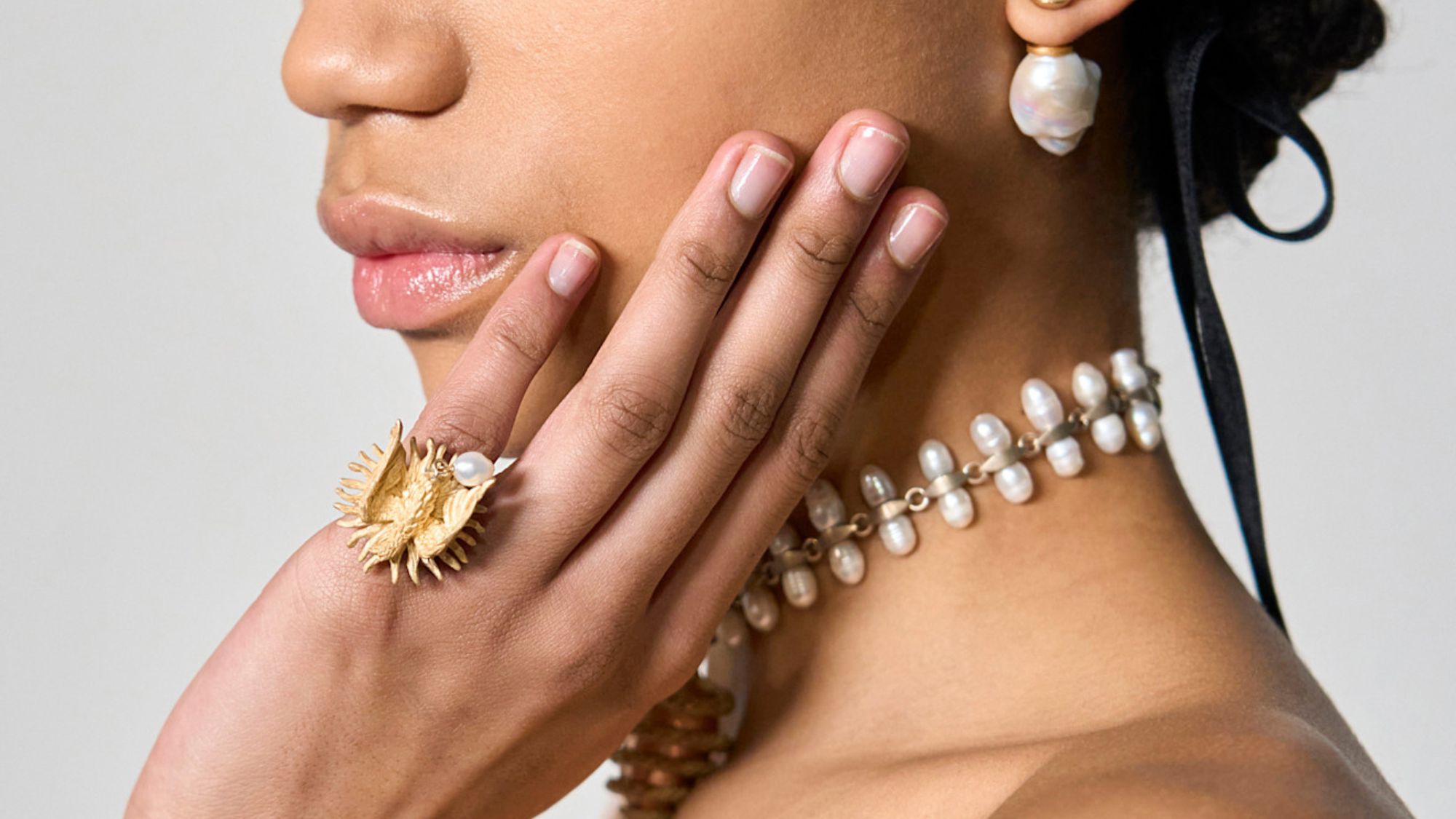 model wearing gold jewellery with plain manicured nails