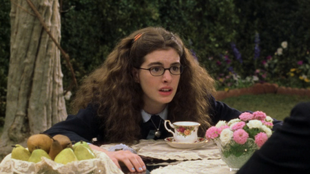 Anne Hathaway as Mia Thermopolis leaning over a table at tea in The Princess Diaries 