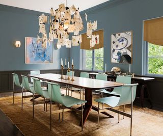 A blue dining room with large glass chandelier hanging from the ceiling