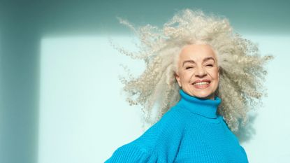 woman with gray curly hair on a blue background