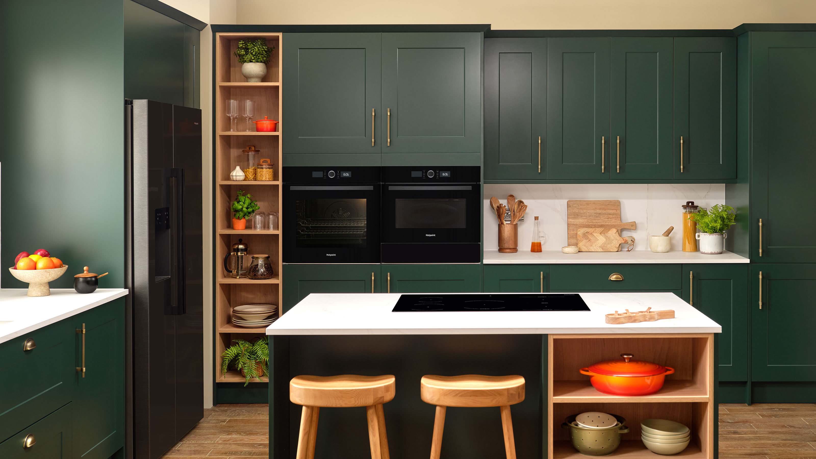 Green kitchen with fitted oven in cabinetry, stainless steel fridge and hob on island
