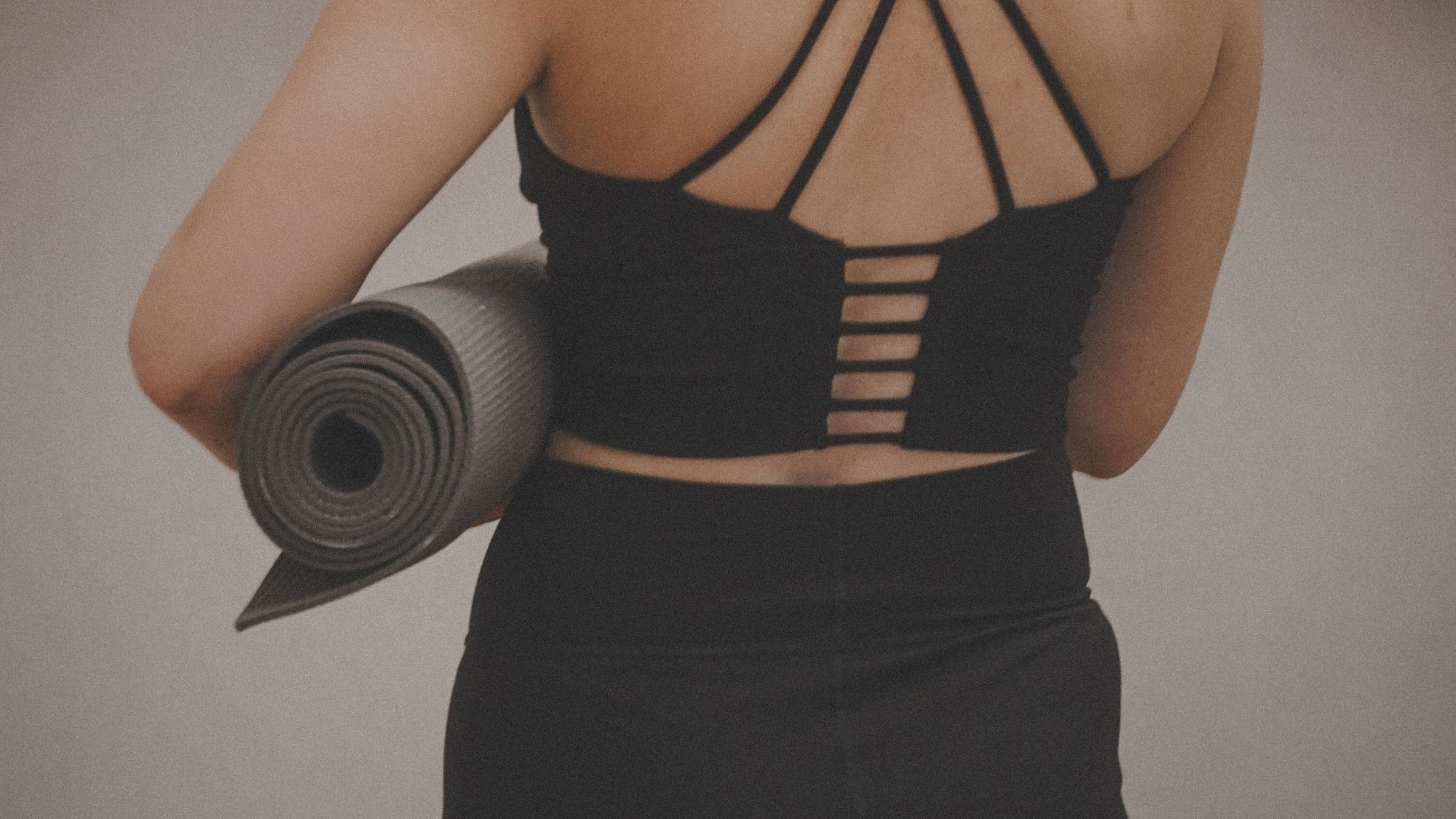 A woman stretching in gym gear with a yoga mat