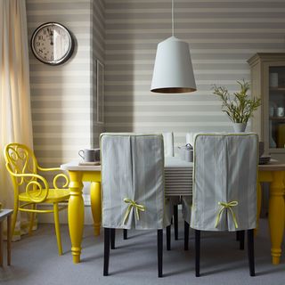 dining room with grey stripped wallpaper and dining table with chairs and clock on wall
