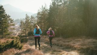 Women running outdoors wearing running backpacks