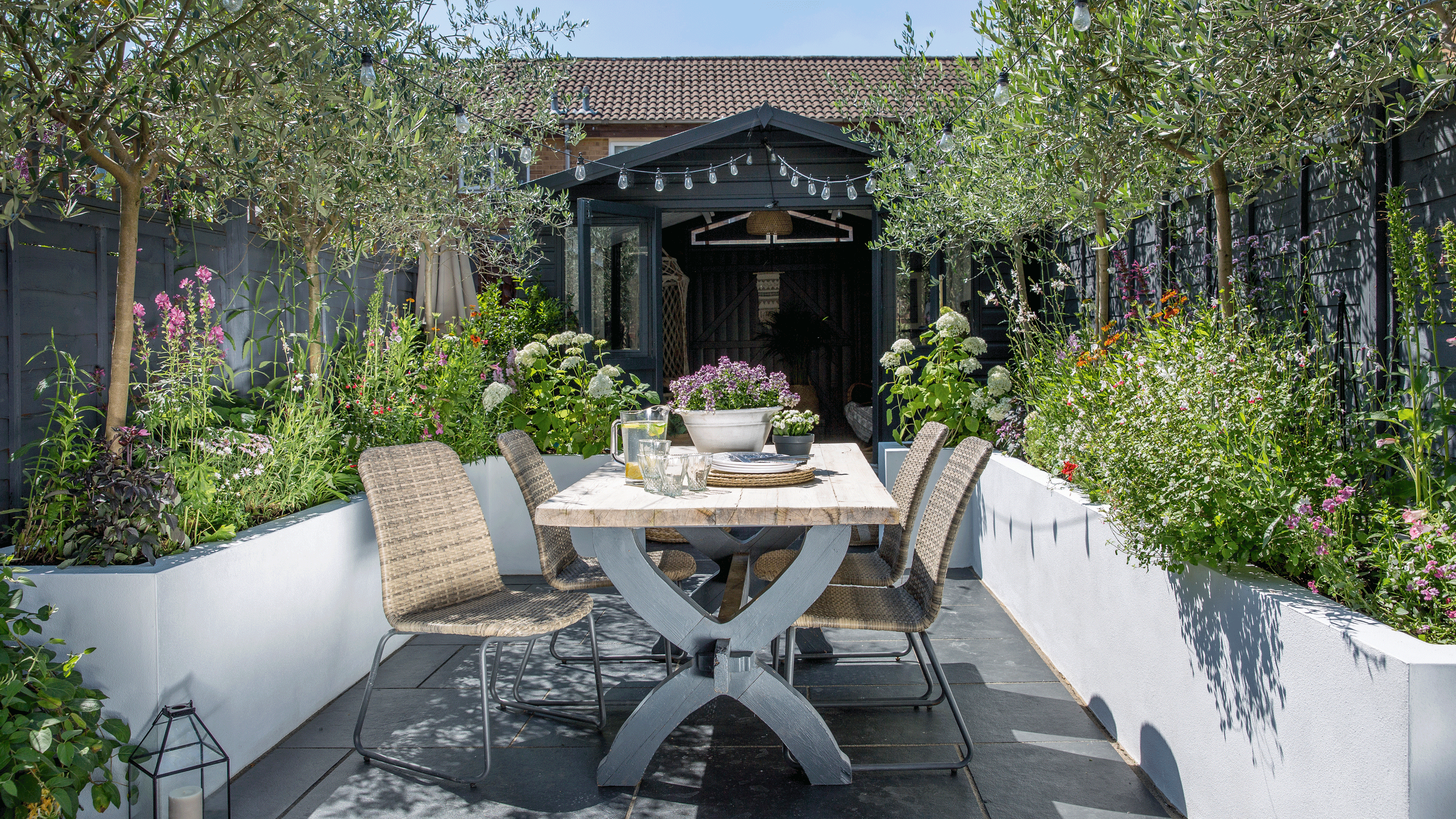 Small garden with white washed raised planters on either side of an outdoor dining table