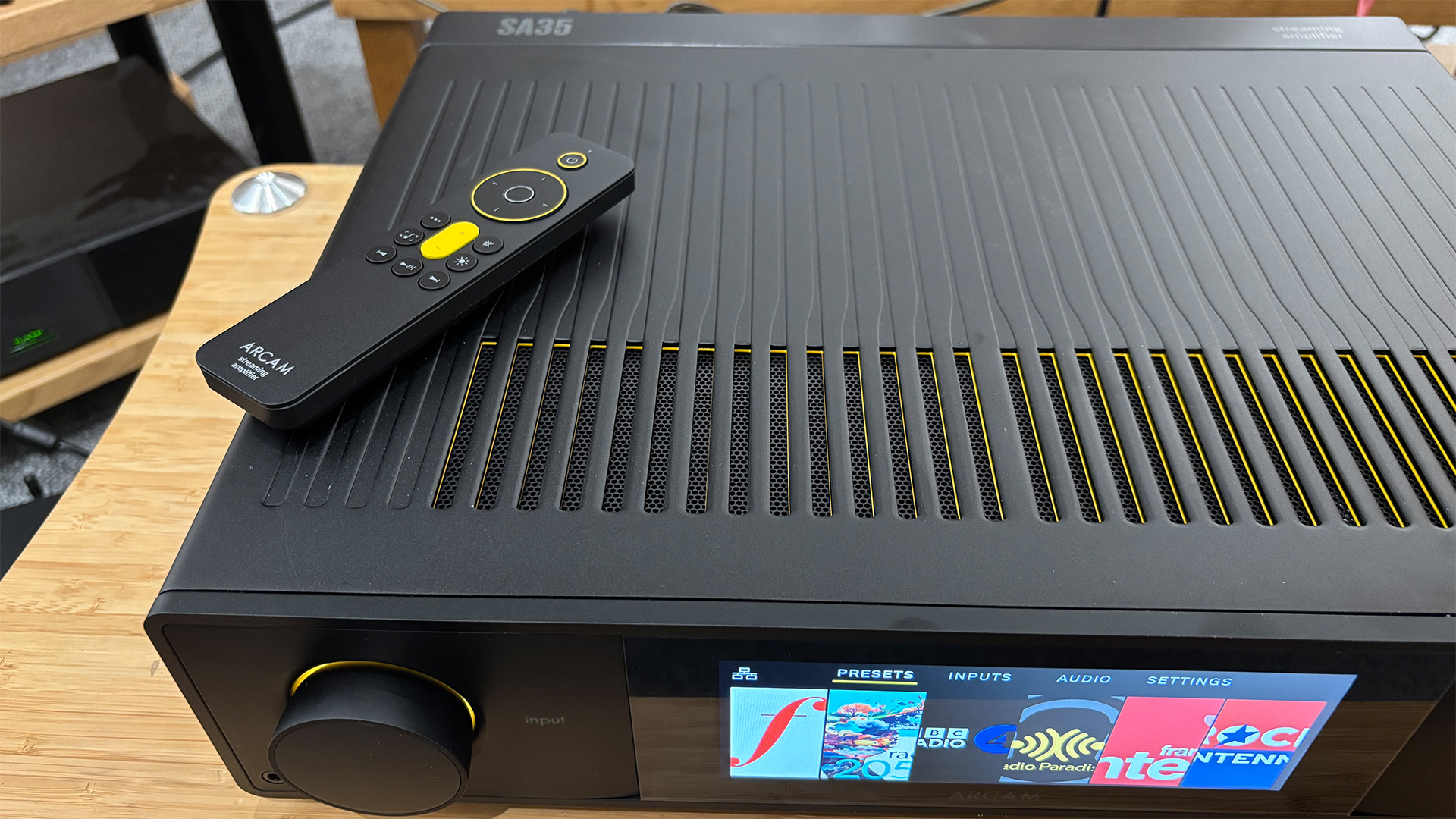 Arcam SA35 music streamer with remote control on top, close up on display and input control