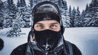 snowboarder covered in snow smiling in winter