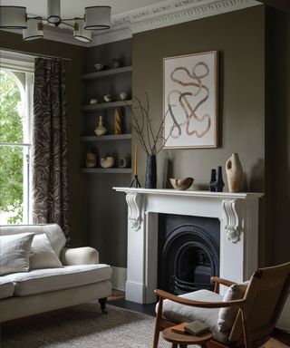 living room with brown-green walls, white fireplace and neutral decor