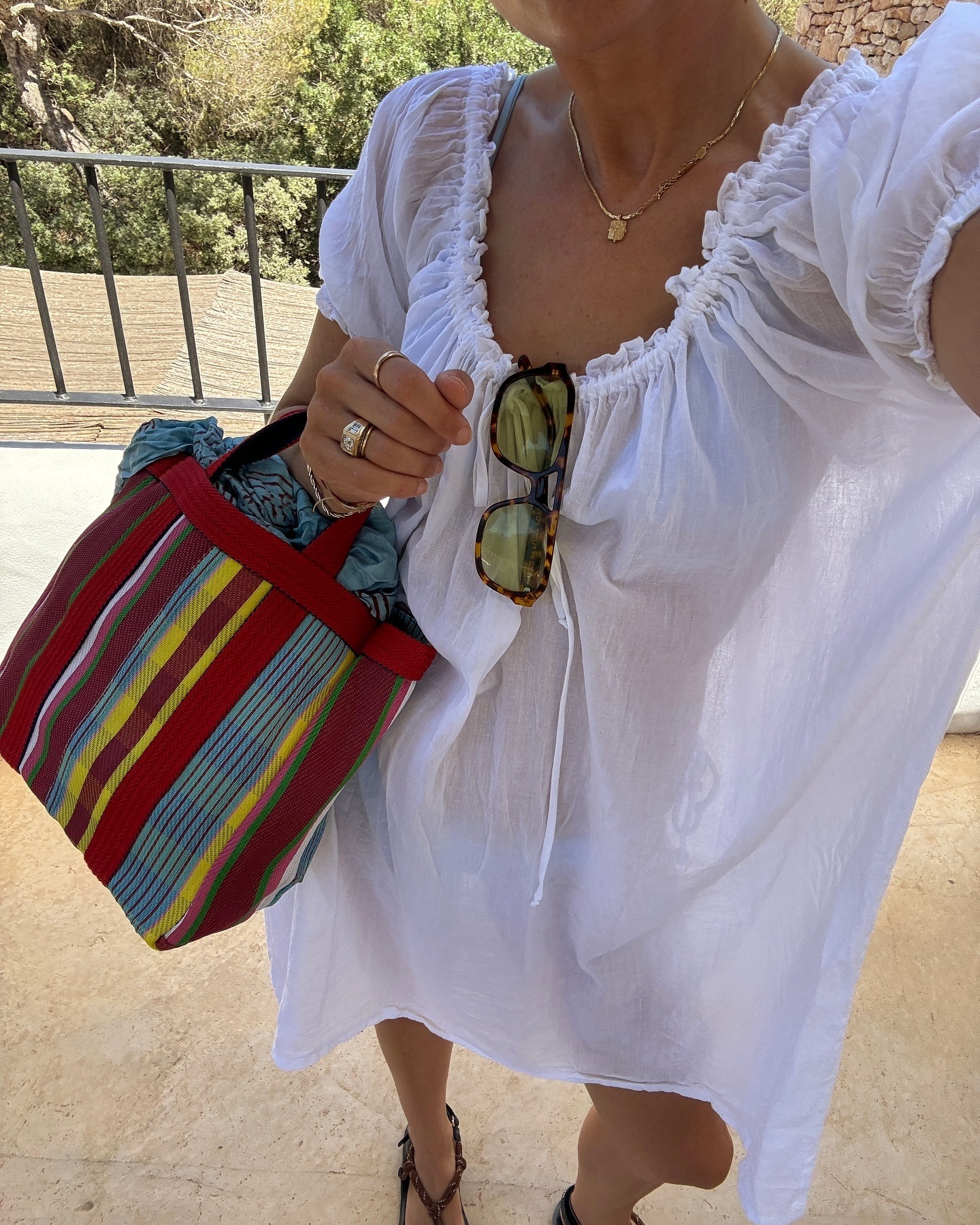 Lucy Williams wearing a white dress and colorful striped market tote bags.