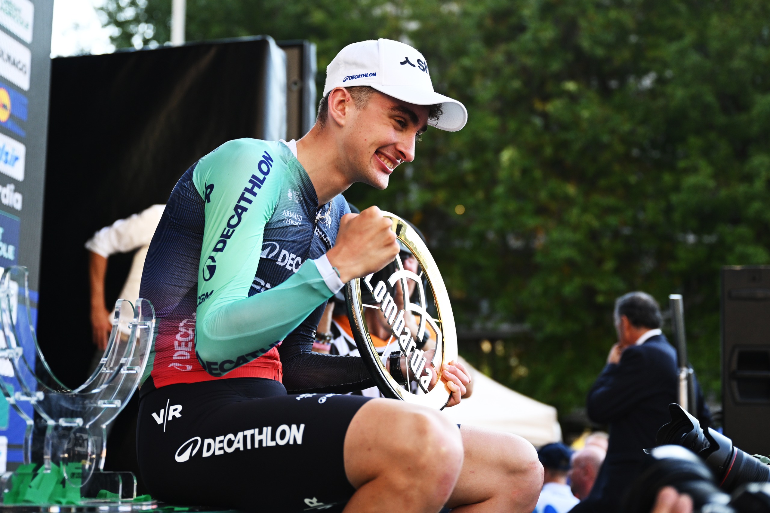 Paul Seixas sits and holds the winner's trophy on the podium after taking victory at Il Lombardia 2026