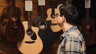 Customer looking at acoustic guitars in a guitar store