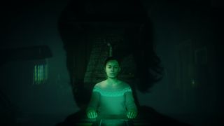 A woman surrounded by green light sits at a table with Alan Wake's head silhouetted behind her