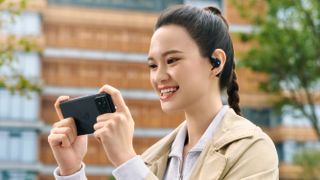 A promotional image showing a woman wearing the Asus Rog Cetra Open Wireless open-ear earbuds.