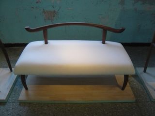 Bench with a smooth, white seat and slim wooden back and legs