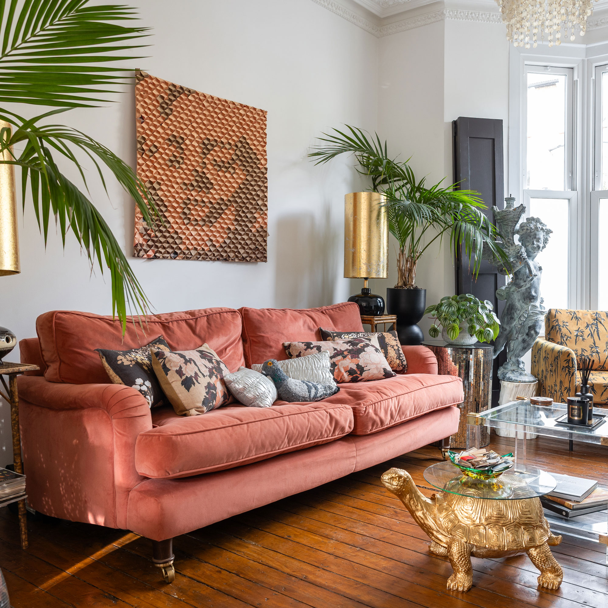Pink sofa with cushions in a white living room with a gold tortoise side table