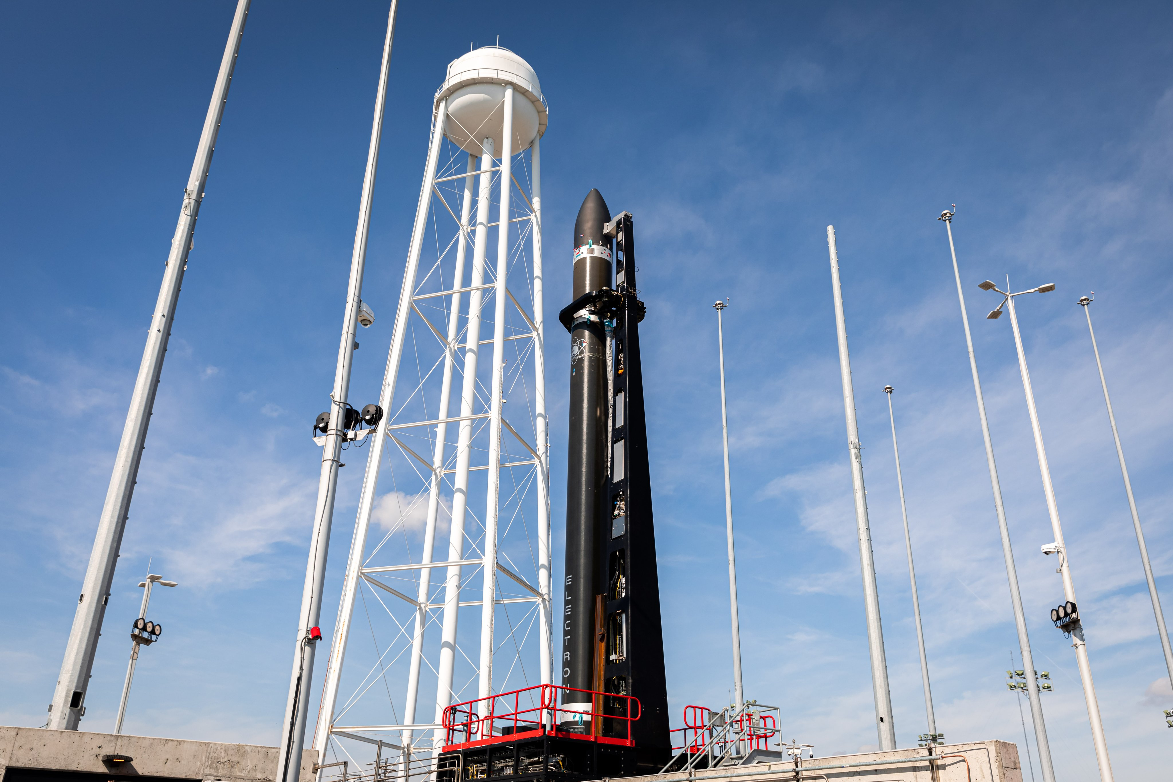 A Rocket Lab Electron rocket on its Virginia launch pad with a blue sky.