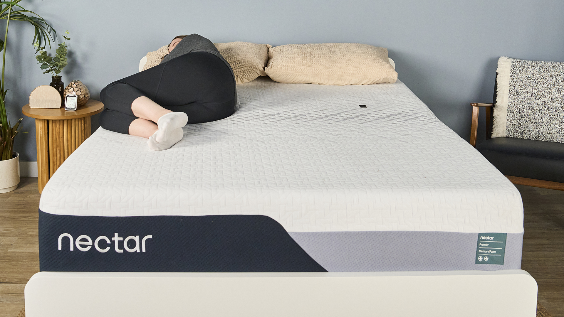 A member of our testing team lying on her side on the Nectar Premier Memory Foam Mattress in our sleep studio