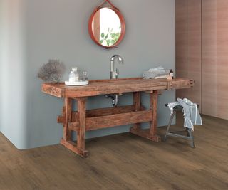 wood effect vinyl flooring in bathroom with large vintage wooden vanity unit against grey wall