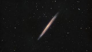 the edge-on profile of the Knife Edge Galaxy is pictured against a distant starfield on a black sky.