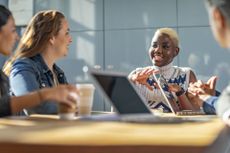 Female colleagues in discussion sitting at a table with their laptops out