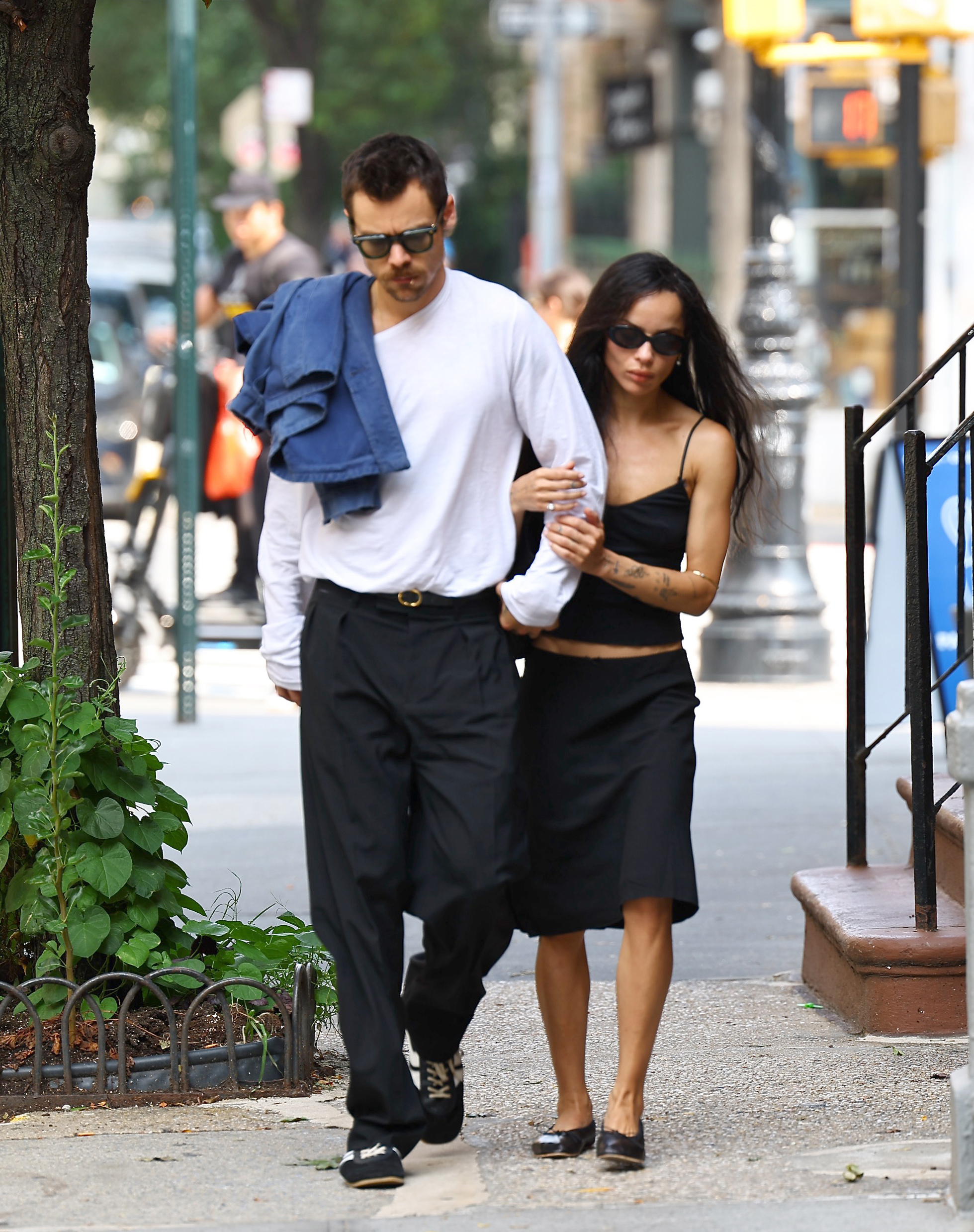 Harry Styles in a white long sleeve shirt and trousers with Zoe Kravitz wearing a skirt and tank top