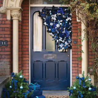 Navy front door with assymetrical wreath on corner.